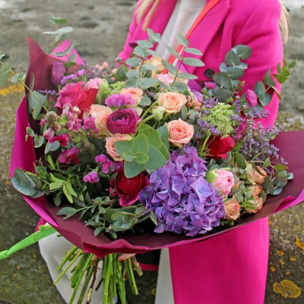 A beautiful bouquet of flowers featuring hydrangea, roses, ranunculus and more with frosty green foliage.