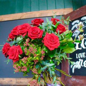 The classic dozen red roses - beautiful, bright red roses in full bloom with plenty of luscious foliage and a sprinkling of tiny flowers for a meadowy feel - perfect for Valentines and other romantic dates.