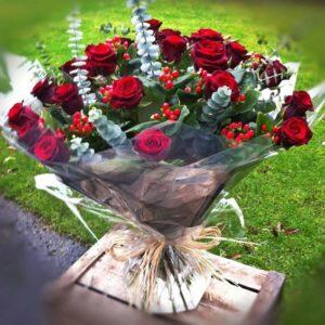 Impressive, large bouquet of two dozen dark red roses combined with lush green foliage, perfect for Valentine's Day and other romantic dates.
