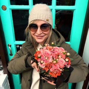 Elegant, vintage, black and gold hatbox containing a posy of vibrant pink roses and other gorgeous blooms.
