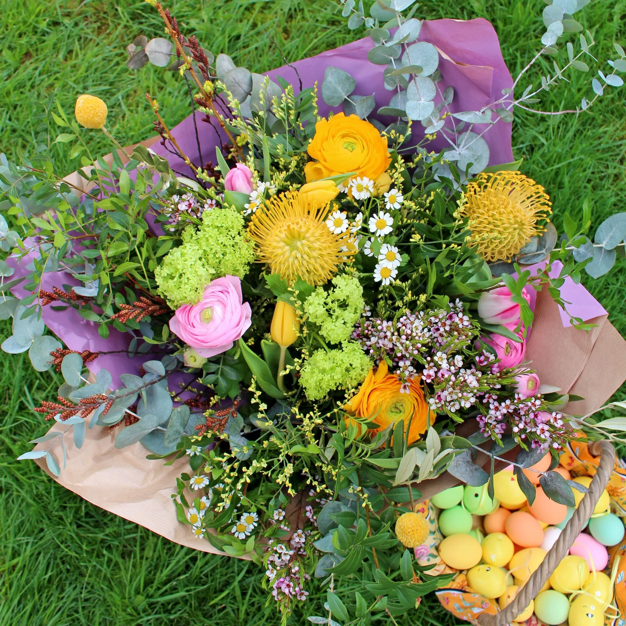 Beautiful spring themed floral bouquet featuring large, bright yellow and pink blooms mixed with cute little meadow flowers and lots of lush greenery.