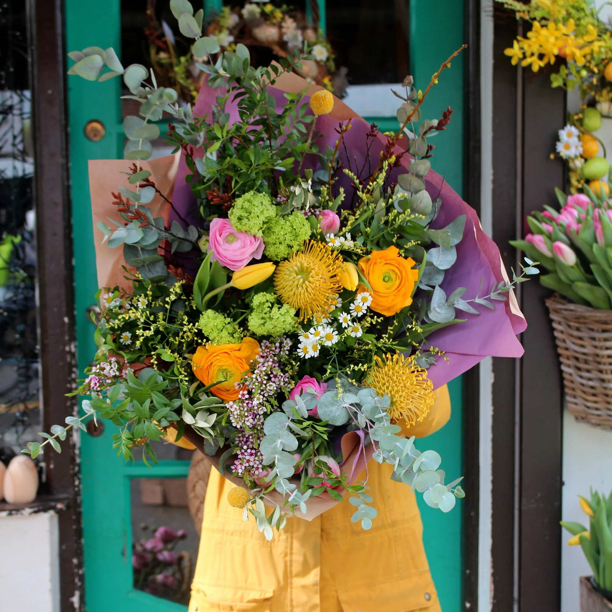 Beautiful spring themed floral bouquet featuring large, bright yellow and pink blooms mixed with cute little meadow flowers and lots of lush greenery.